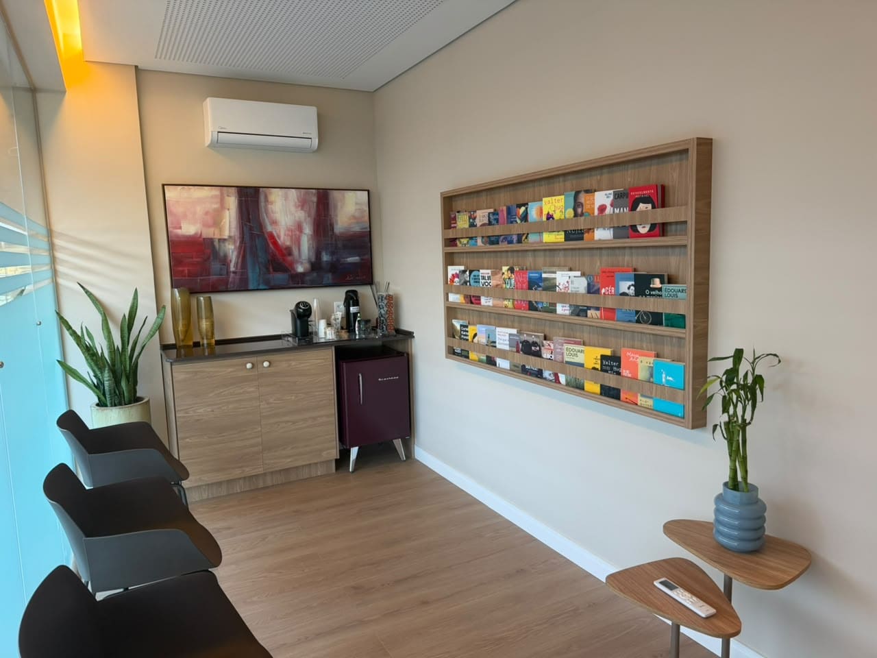 Sala de espera com cadeiras, plantas e a parede de livros