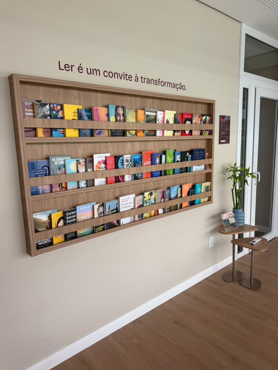 Parede de livros vista de lado, com a frase Ler é um convite à transformação
